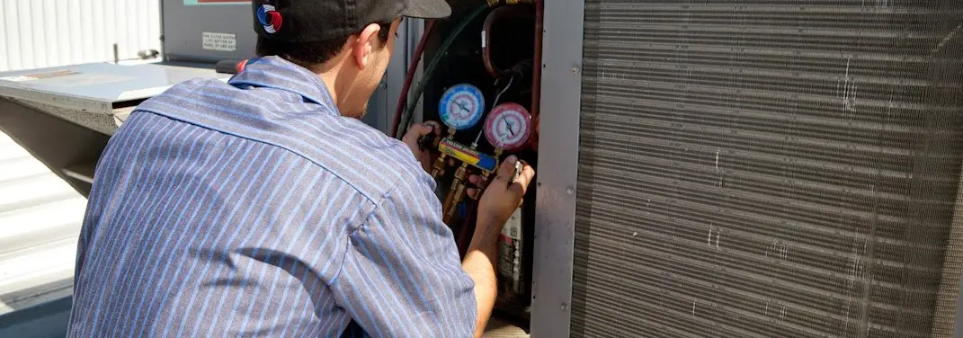 HVAC technician servicing a condenser unit in Linton Hall