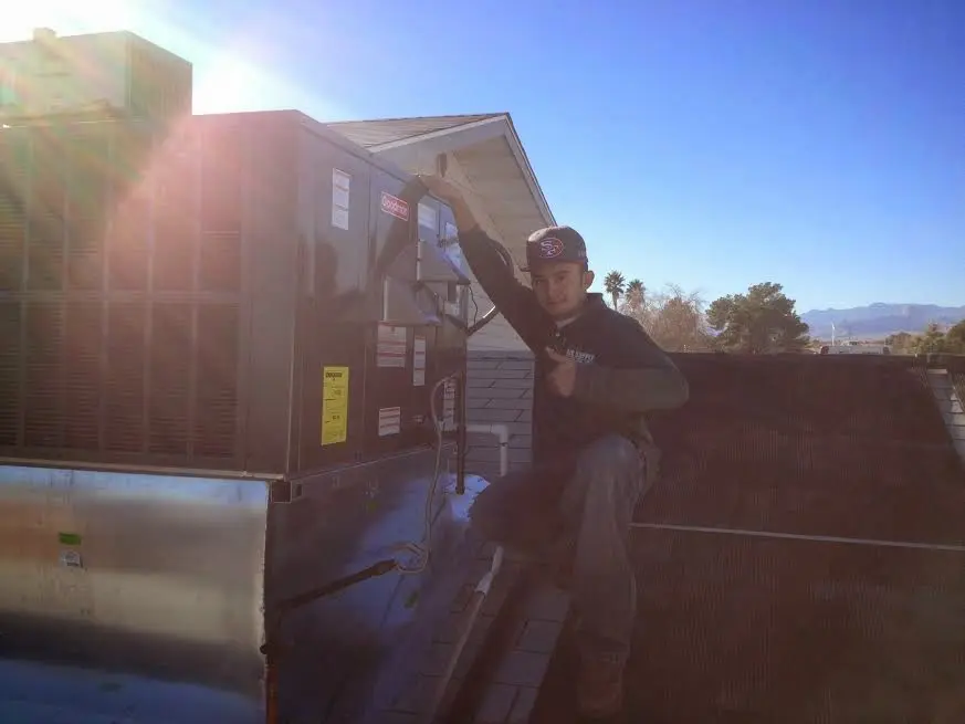 HVAC technician performing AC Tune-Up on a rooftop unit in Linton Hall